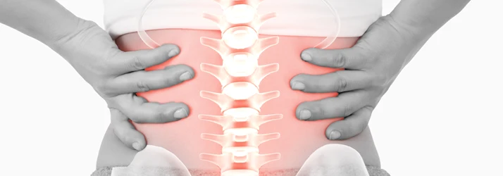 Close-up of a person holding the lower back with both hands, with a red highlighted spine over the central area.