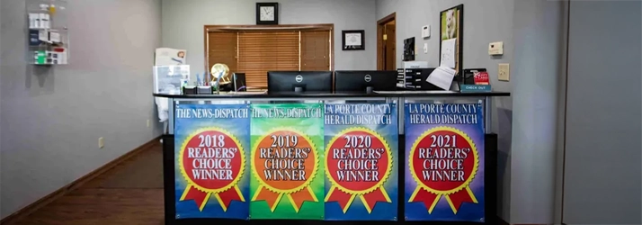 Reception desk with four posters reading “Readers’ Choice Winner” for years 2018 to 2021, computers and office items behind.